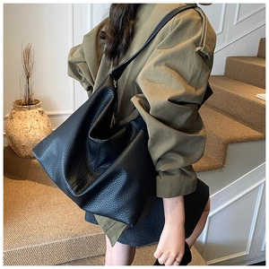Detail of black lychee grain leather Hobo bag with gold zipper and wide shoulder strap