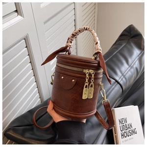 Détail d'un sac seau vintage en cuir marron avec anse en foulard de soie et pendentif cadenas doré