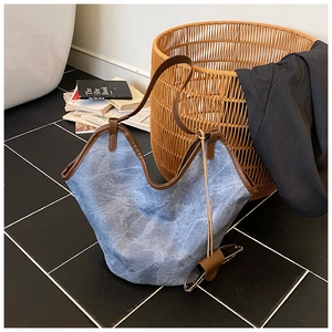 Detail view of large blue washed bucket bag with contrasting brown leather trim