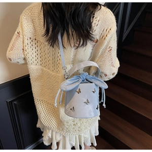 Detail of light blue bucket bag with silver butterfly charms and large bow drawstring