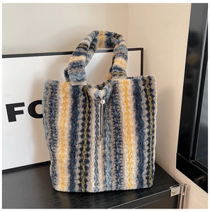 Macro detail of vertical striped plush tote bag featuring soft faux fur and metal charm