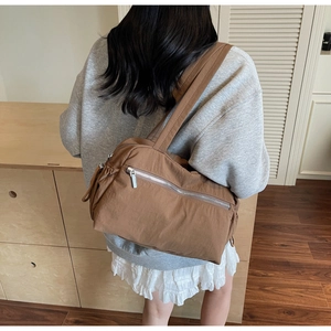 Rear view of a dark brown nylon tote bag featuring a silver zipper and side drawstring