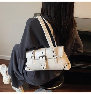Detailed back view of white leather underarm bag with black metal buckles and rivets