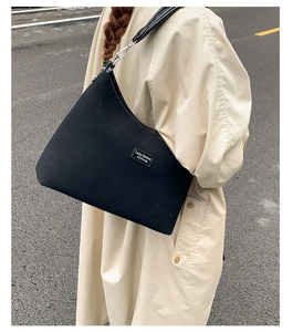 Detail of black canvas tote bag showing thick texture and black leather shoulder strap