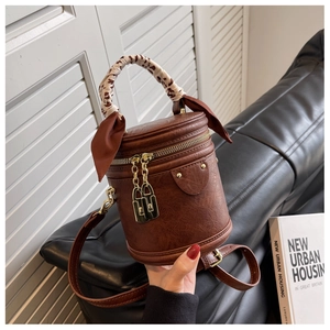 Détail du sac seau vintage marron avec anse en foulard léopard et breloques dorées