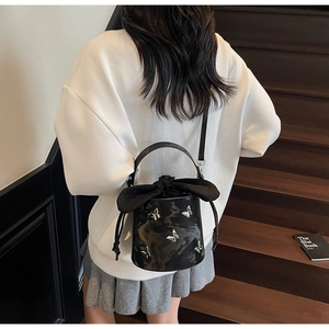 Close-up of black bucket bag with silver butterfly metal charms and satin drawstring