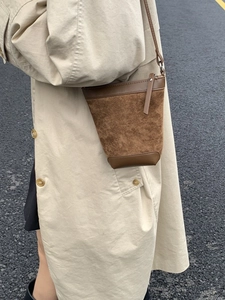 Retro brown frosted bucket bag with leather trim worn by model in beige trench coat
