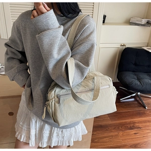 Minimalist off-white tote bag with functional pockets worn over the shoulder in daily life