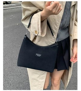 Close-up of black retro matte shoulder bag with Lazy Breeze label in a street style setting