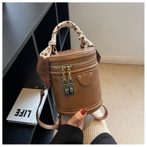 Détail d'un sac seau marron avec serrures dorées et poignée en foulard imprimé animal