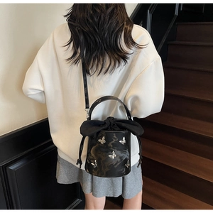 Black glossy bucket bag with silver butterfly charms and satin drawstring detail