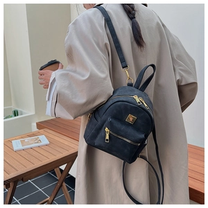 Detailed close-up of a vintage black mini backpack with gold zippers and matte leather texture