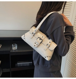 Detail of white leather shoulder bag with large metal buckle and rivet accents