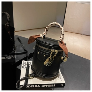 Détail du sac seau cylindrique noir avec poignée en foulard de soie et métal doré