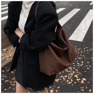 Detail view of a large brown leather hobo bag showing litchi texture and spacious design