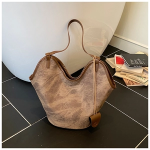 Detail of light brown retro bucket bag with curved rim and decorative mini pouch accessory