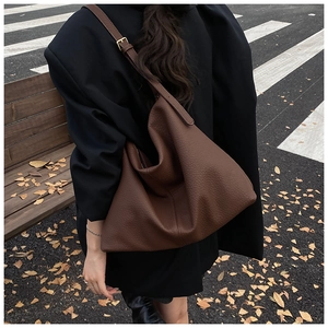 Deep brown textured leather tote bag showing spacious capacity and metallic buckle detail