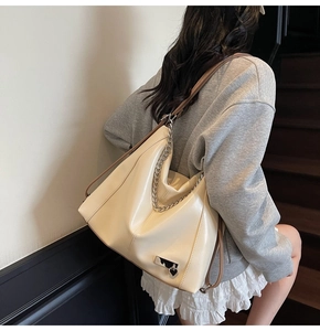 Vue détaillée du sac cabas crème avec chaîne et détails argentés porté par un mannequin