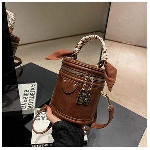 Détail du sac seau marron caramel avec foulard en soie léopard enroulé sur l'anse