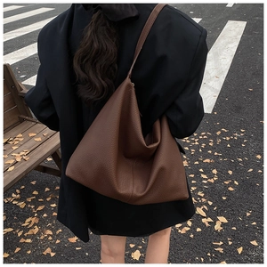 Macro view of textured brown leather tote bag with subtle pebbled finish and handle detail