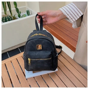 Detailed view of black matte backpack featuring gold-tone zippers and metal logo hardware