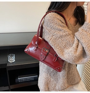 Detail view of burgundy faux leather shoulder bag with metallic studs on a model