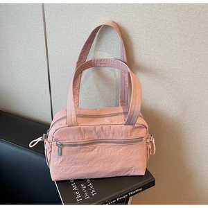 Detail of pink nylon shoulder bag showing multiple zipper pockets and drawstring side bag