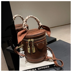 Detail of vintage brown bucket bag with leopard scarf handle and metal zippers
