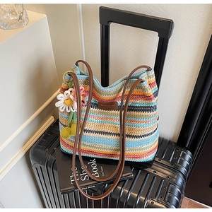 Detail der mehrfarbig gestreiften gewebten Strandtasche mit Blumenanhänger und Ledergurt
