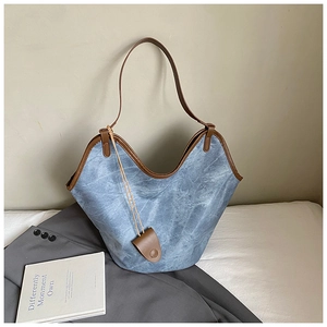 Detail of vintage blue washed canvas tote bag with brown leather handles and charm