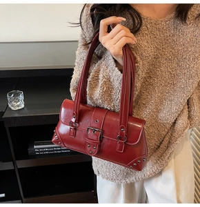 Close-up of vintage dark red shoulder bag featuring wax finish leather and silver buckle