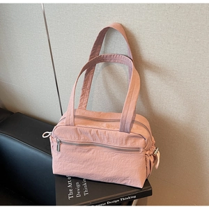 Detail of light pink nylon shoulder bag showing metal zippers and drawstring texture