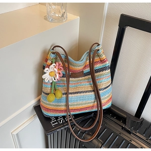 Makro-Detail einer bunten gewebten Tasche mit Lederriemen und Gänseblümchen-Anhänger