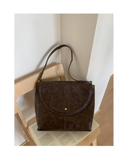 Détail d'un sac cabas marron vintage avec boucle dorée sur une chaise en bois chic