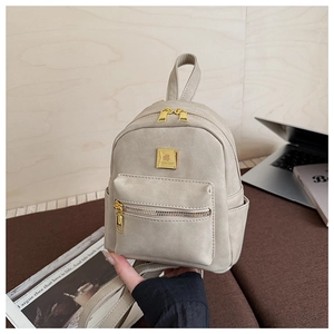 Detail of small vintage beige backpack with gold metal logo and premium leather texture