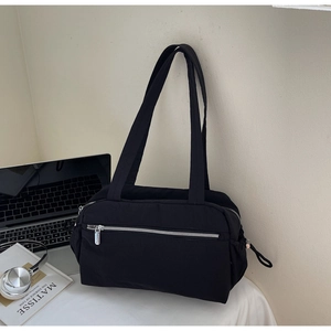 Detail of minimalist black nylon shoulder bag with silver zipper and side drawstrings