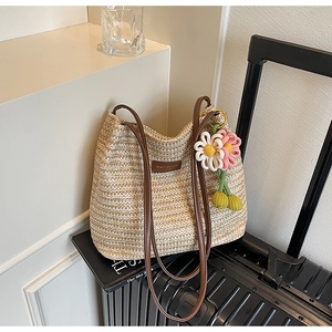 Detail der handgewebten Strohtasche mit Lederriemen und dekorativem Kirsch-Blumen-Anhänger