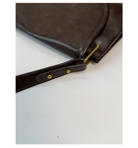Détail d'un sac en cuir rétro marron foncé avec boucle en métal doré et rivets de fixation