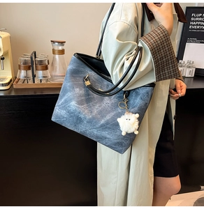 Detail of blue denim tote bag with leather handles shown in a lifestyle cafe setting