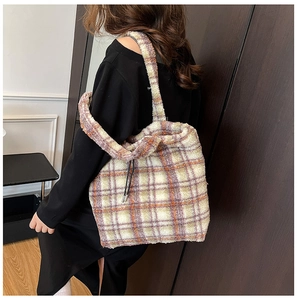 Detail of soft plush plaid tote bag in beige and purple on a model's shoulder