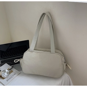 Detail of a beige quilted tote bag with drawstring accents for daily commute and work