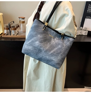 Detail view of the blue-grey marble texture fabric and black leather shoulder strap on a tote bag