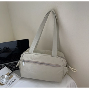 Detail of minimalist beige nylon tote bag featuring front silver zipper and drawstring sides