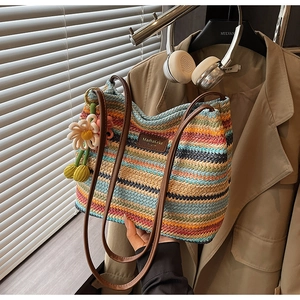 Detail einer gestreiften Web-Beuteltasche mit 3D-Blumenanhängern und braunen Lederriemen