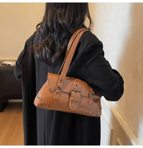 Caramel brown vintage hobo bag with metal buckle and rivet details worn on shoulder