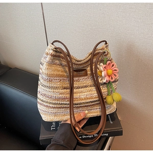 Detail der handgewebten gestreiften Strandtasche mit Ledergriffen und Häkelblumen-Anhänger