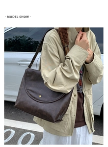 Détail d'un sac bandoulière vintage marron foncé avec une grande boucle en métal doré