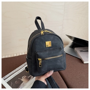 Close-up of mini black faux leather backpack with gold zippers and metal logo plate detail