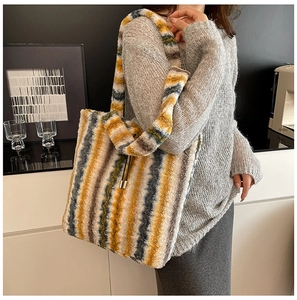 Detail view of colorful fuzzy striped tote bag worn by a model in a modern interior