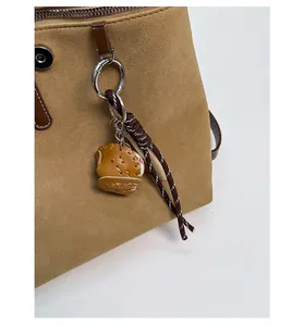 Dettaglio di un ciondolo a guanto da baseball su uno zaino color kaki opaco